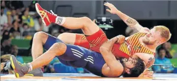  ?? PTI ?? India's Bajrang Punia (in blue) grapples with Wales' Kane Charig in men's freestyle 65 kg final on Friday.