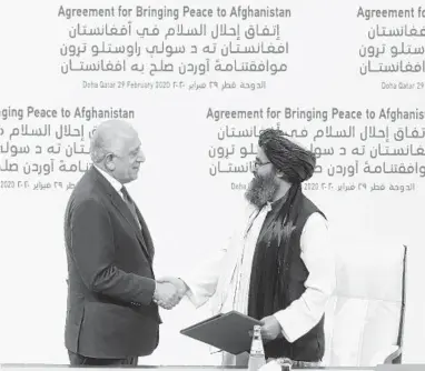  ?? HUSSEIN SAYED/AP ?? U.S. peace envoy Zalmay Khalilzad, left, and Mullah Abdul Ghani Baradar, the Taliban group’s top political leader, shake hands Saturday after signing a peace agreement that would end America’s longest war in Doha, Qatar.