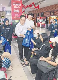  ?? — Gambar Chimon Upon ?? TERIMALAH: Chong berpeluang memberi buah tangan kepada penumpang bas di Terminal Bas Kuching Central semasa program tersebut semalam.