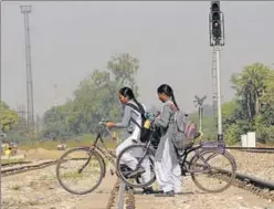  ?? BHARAT BHUSHAN/HT ?? OFF TRACK: Two school girls are oblivious to the red signal as they cross the tracks near the DieselLoco Modernisat­ion Works (DMW) in Patiala on Thursday.