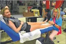  ??  ?? Diane Stone gives a foot massage to one of the first walkers to cross the finish line