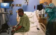  ??  ?? A COVID-19 patient sits up on his bed during an exercise session with a physical therapist in Orange, Calif.