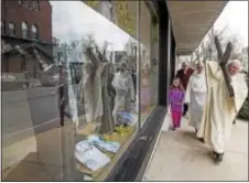  ?? RICK KAUFFMAN — DIGITAL FIRST MEDIA ?? Reflected in the windows of B. Gross in downtown Media, Rev. Edward H. Bell leads a procession on Good Friday through the streets.