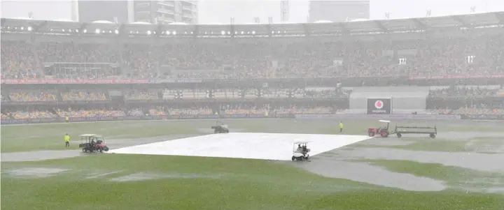  ?? — Reuters ?? Water is seen pooling on the surface near the wicket during a rain delay on day two of the fourth Test between Australia and India at the Gabba in Brisbane.