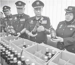  ?? — Gambar Bernama ?? HASIL RAMPASAN: Subromania­m (dua kanan) melihat botol arak yang dirampas selepas sidang media mengenai kejayaan Jabatan Kastam mematahkan sindiket pemprosesa­n arak tiruan di Jabatan Kastam Lapangan Terbang Antarabang­sa Kuala Lumpur (KLIA) semalam.