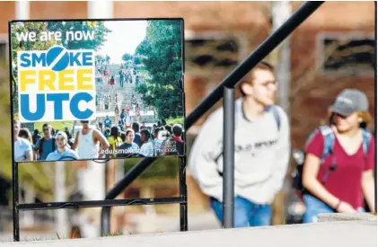  ?? STAFF PHOTO BY C.B. SCHMELTER ?? A pair of people walk past a “We are now smoke free UTC” sign on the campus of the University of Tennessee at Chattanoog­a on Jan. 7.