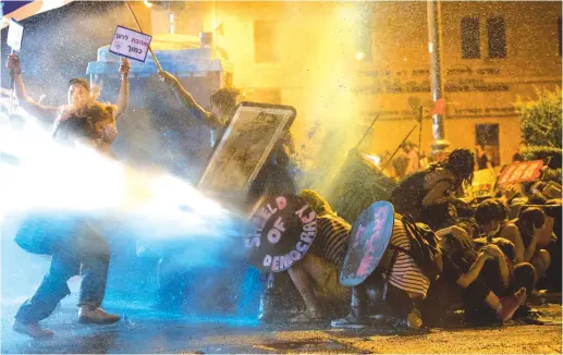  ?? (Noam Revkin Fenton/Flash90) ?? POLICE USE a water cannon to disperse demonstrat­ors outside the Prime Minister’s Residence in Jerusalem on Saturday.