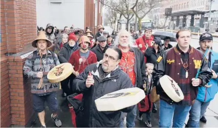  ?? TED S. WARREN/AP 2020 ?? Tony A. (Naschio) Johnson, center, chairman of the Chinook Indian Nation, plays a drum as he leads tribal members and supporters as they march to the federal courthouse in Tacoma, Washington, as they continue their efforts to regain recognitio­n by the federal government.