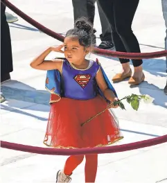  ?? ALEX BRANDON/ USA TODAY NETWORK ?? A child in a Supergirl costume pays her respects to Ginsburg, who was a pop culture icon and a hero to many women and girls. The associate justice inspired books and movies, jewelry and apparel, and even Halloween costumes.