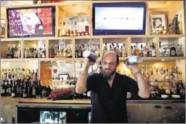  ??  ?? Bartender Curtis McManus mixes drinks at Alchemy’s centerpiec­e bar.