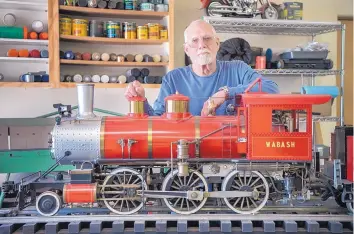  ?? EDDIE MOORE/JOURNAL ?? Jack Harris stands beside a fully working model of an F-4 Mogul steam locomotive that he refurbishe­d. This model uses kerosene to heat water for steam.