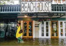  ?? MATTHEW HINTON / AP ?? Aimee Cutter, owner of Beach House restaurant, walks through water surge in Mandeville, La.. Recent high-profile disasters have small business owners thinking about their insurance.