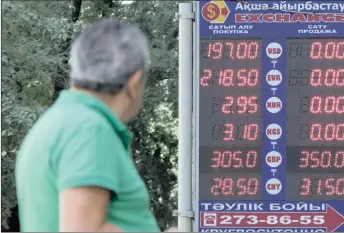  ?? PHOTO: REUTERS ?? A man walks past a board showing currency exchange rates in Almaty, Kazakhstan. Kazakhstan’s tenge lost almost a quarter of its value yesterday after the central Asian nation introduced a freely floating exchange rate for the currency.