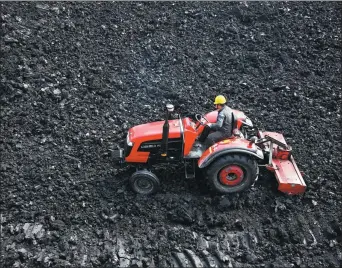  ?? WU HE / FOR CHINA DAILY ?? A man operates a tractor to crush coal, one of the fuels used by the thermal power industry, in Huaibei, Anhui province.