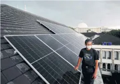  ?? ?? Solar panel technician Adi Purwanto walks on the roof of the Jakarta Cathedral.