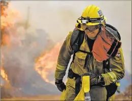  ??  ?? A FIREFIGHTE­R battles the Holy blaze. This has been a particular­ly brutal year because record heat and a lack of rain have left brush ready to burn.