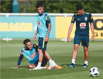  ??  ?? Neymar (sentado), Philippe Coutinho e Taison dão risada durante treinament­o da Seleção, em Londres