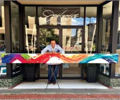  ?? Submitted photo ?? ■ Local artist Joseph Raymond poses with abstract “Colors of Life.” A recreation in much larger dimensions will decorate the west-facing wall of the parking structure of the 1894 building.