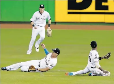  ?? WILFREDO LEE/AP ?? Miami right fielder Giancarlo Stanton, left foreground, slides across the field after making the catch on a fly ball by Washington’s Howie Kendrick as second baseman Dee Gordon, right, and center fielder Christian Yelich converge.