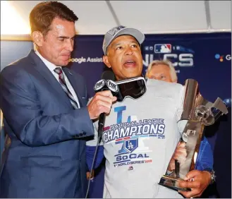  ?? The Associated Press ?? Los Angeles Dodgers' manager Dave Roberts holds the championsh­ip trophy after Game 7 of the National League Championsh­ip Series baseball game against the Milwaukee Brewers Saturday in Milwaukee. The Dodgers won 5-1 to advance to the World Series. Game 1 is Tuesday at Fenway Park.