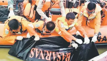  ??  ?? Members of a rescue team retrieving a body from the Musi river in Palembang, after the boat hit a large wave and sank amid bad weather. — AFP photo