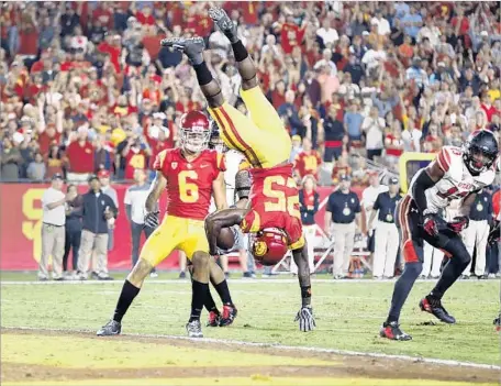  ?? Photograph­s by Allen J. Schaben Los Angeles Times ?? USC’S RONALD JONES II goes over Utah’s Marquise Blair on a fourth-quarter touchdown as teammate Michael Pittman watches.