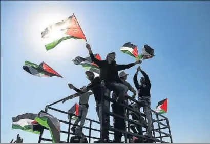  ?? ANADOLU AGENCY / GETTY ?? Palestinos haciendo ondear su bandera en Ramala en un acto el pasado febrero