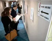  ?? STEVE SCHAEFER / SPECIAL TO THE AJC ?? Kimberly Gibbs (left) fills out her paperwork before voting at the DeKalb County Library-Dunwoody Branch on Oct. 27. Manager Renata Fleming said 174 people voted there in the first hour.