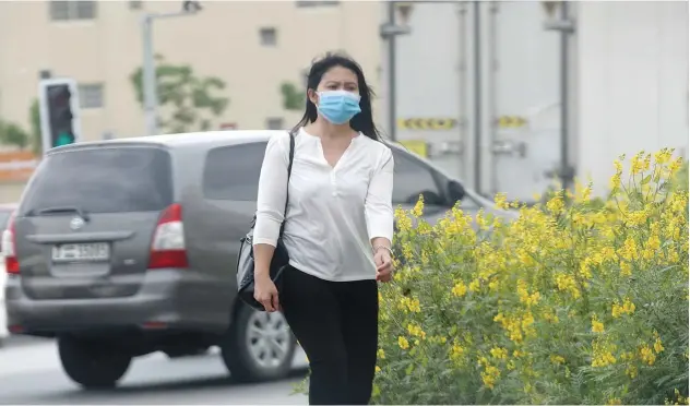  ?? Kamal Kassim/ Gulf Today ?? ↑
A woman walks toward her home wearing her protective mask.