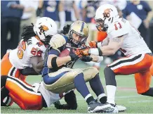  ?? POSTMEDIA NEWS/ FILES ?? Solomon Elimimian, left, and Alex Hoffman- Ellis take down Winnipeg quarterbac­k Drew Willy. Elimimian has been lost to the Lions for the season after suffering an Achilles injury.