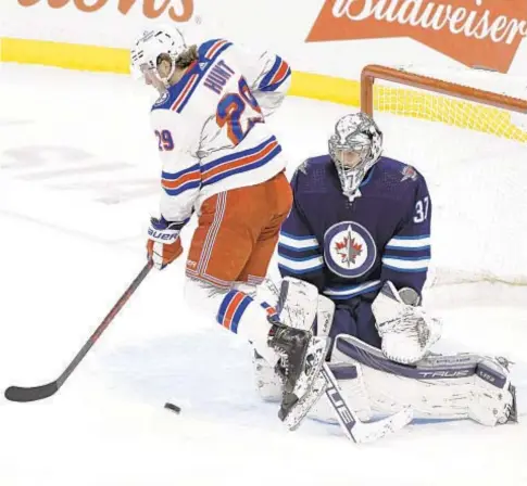  ?? AP ?? Rangers’ Dryden Hunt jumps out of way as deflected shot gets past Jets goaltender Connor Hellebuyck in third period Sunday in Winnipeg.