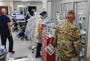  ?? Jerry Lara / Staff photograph­er ?? Brooke Army Medical Center emergency room personnel observe a COVID-19 patient in an isolation room. Trauma patients from University Hospital now are being sent to BAMC.