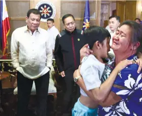  ?? /MALACANANG PALACE VIA AP ?? REUNION. President Rodrigo Duterte, left, looks at released 8-year-old hostage Rexon Romoc being reunited with his mother. Duterte said a massive offensive backed by fighter jets against the extremists was underway.