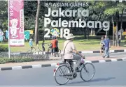  ??  ?? A cyclist rides past an installati­on promoting the upcoming Asian Games, to be held in Jakarta and Palembang.