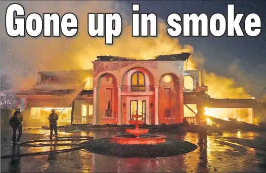  ?? ?? LINE OF FIRE: California firefighte­rs hose down a burning home in Laguna Niguel, where stretches of the coastal city are caught in wind-driven blazes.