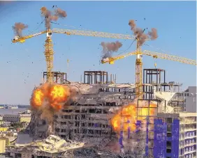  ?? DAVID GRUNFELD/THE ADVOCATE ?? Explosions go off Sunday as part of the demolition of two large cranes at the site of the Hard Rock Hotel collapse in New Orleans. Before the cranes fell, they were looming precarious­ly over the partially collapsed hotel.