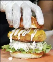  ?? ALAN DIAZ — THE ASSOCIATED PRESS ?? In this photo, a handler tops a Krispy Fried Chk’n sandwich with a doughy pretzel bun in Miami. The fare is popular among vegans and vegetarian­s who long for greasy comfort food, but abstain for ethical reasons.