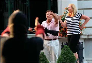  ?? The Associated Press ?? UNLAWFUL USE: In this June 28 file photo, armed homeowners Mark and Patricia McCloskey, standing in front their house along Portland Place confront protesters marching to St. Louis Mayor Lyda Krewson’s house in the Central West End of St. Louis. St. Louis’ top prosecutor told The Associated Press on Monday, that she is charging a white husband and wife with felony unlawful use of a weapon for displaying guns during a racial injustice protest outside their mansion.