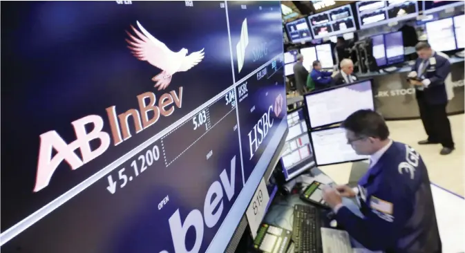  ??  ?? NEW YORK: The ABInBev logo appears above the post where it trades on the floor of the New York Stock Exchange. Global stock markets mostly climbed yesterday and the dollar surged to multi-month highs with traders shrugging off concerns over the Trump...