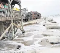  ??  ?? Whittney Chaney (left) and Lanae Damron watch the heavy surf go underneath their rental house during high tide in North Topsail Beach, North Carolina, yesterday.