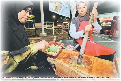  ?? — Gambar Bernama ?? KERJASAMA: Rosnah Mat Saman (kanan) menumbuk bahan-bahan membuat kebebe sambil dibantu adiknya Rohana.