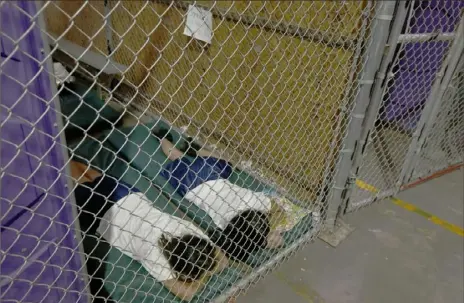  ?? Ross D. Franklin/Associated Press ?? Two female detainees sleep in a holding cell June 18, 2014, as hundreds of mostly Central American immigrant children are processed and held at the U.S. Customs and Border Protection Nogales Placement Center in Nogales, Ariz.