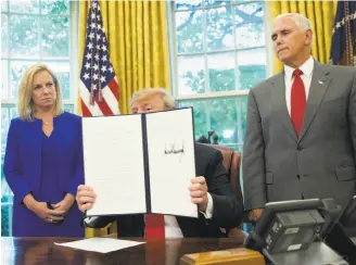  ?? Pablo Martinez Monsivais / Associated Press ?? President Trump, with Homeland Security Secretary Kirstjen Nielsen and Vice President Mike Pence, holds up an executive order he signed to end family separation­s at the border.