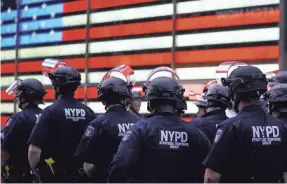  ?? TIMOTHY A. CLARY/AFP VIA GETTY IMAGES ?? New York police officers watch demonstrat­ors in Times Square on June 1, during a “Black Lives Matter” protest.