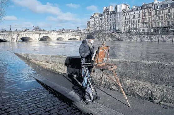  ?? Christophe archambaul­t/aFp ?? Un pintor retrató ayer el desborde del Sena, en uno de sus máximos niveles históricos