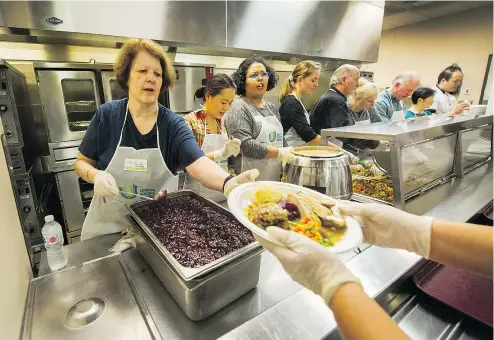  ?? ARLEN REDEKOP/PNG ?? Volunteer Michelle Renaud puts on the finishing touches (including cranberry sauce) and hands plates to servers as thousands attend Thanksgivi­ng dinner on Monday at the Union Gospel Mission.