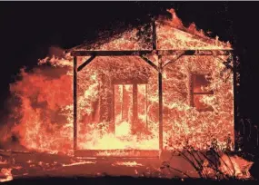  ?? JOSH EDELSON, AFP/GETTY IMAGES ?? Flames overtake a structure as nearby homes burn Monday in the Napa wine region in California. Wind-driven fires whipped through the region.