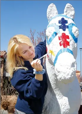  ?? NWA Democrat-Gazette/DAVID GOTTSCHALK ?? Savvy Shields, a volunteer with Equestrian Bridges, helps Monday paint the horse in front of Northwest Arkansas Florist on College Avenue in Fayettevil­le. The nonprofit organizati­on is painting the horse to bring attention to Autism Awareness Month and...