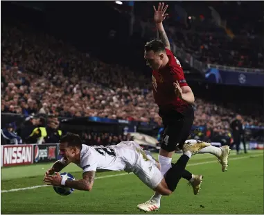  ??  ?? Phil Jones fouls Santi Mina on a night to forget for Manchester United defender, whose own goal proved to be Valencia’s winner