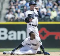  ??  ?? Jean Segura of the Mariners holds his ankle after sliding into second base as he and first base coach Casey Candaele wait for training staff during the fourth inning of a game against the Colorado Rockies at Safeco Field on Thursday in Seattle, Wash.